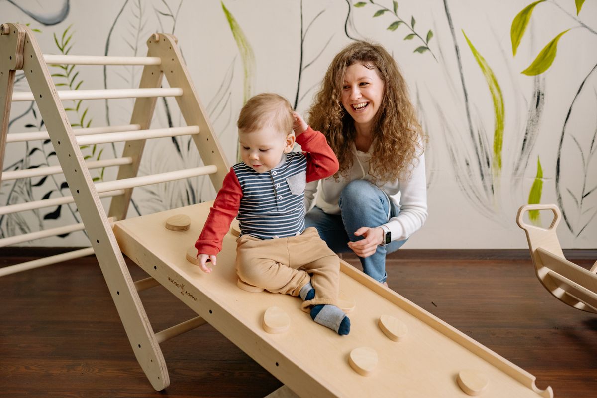 A joyful interaction between a mother and her child on a wooden playground indoors, nurturing happiness.