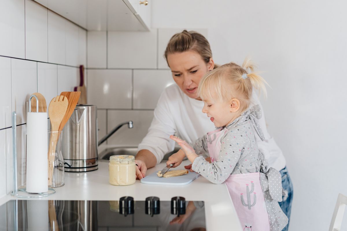 Una madre e un bambino che indossano grembiuli preparano il cibo in una cucina accogliente.