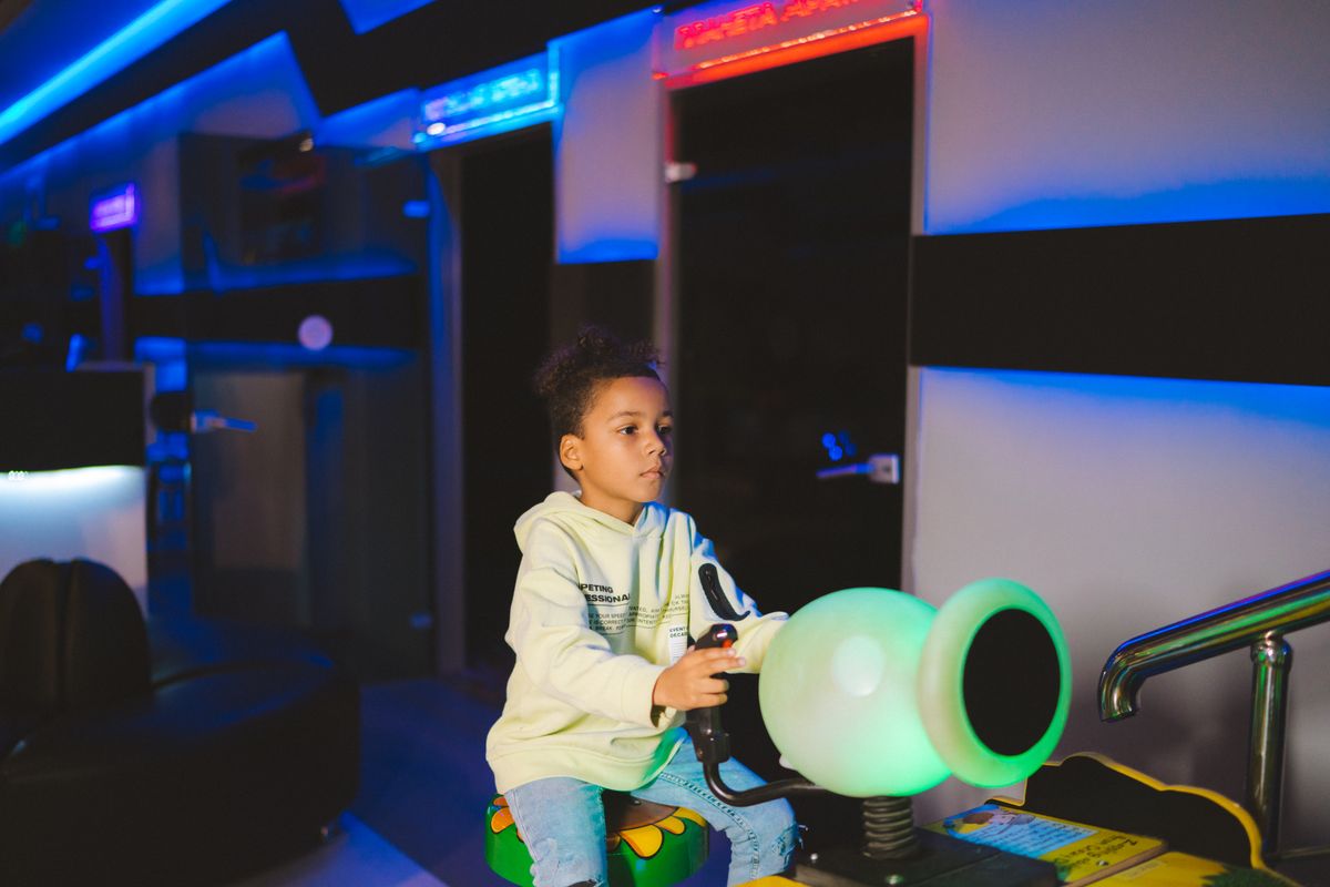 Child playing a video game in an arcade, focused on the screen. - Photo by Anastasia  Shuraeva on Pexels
