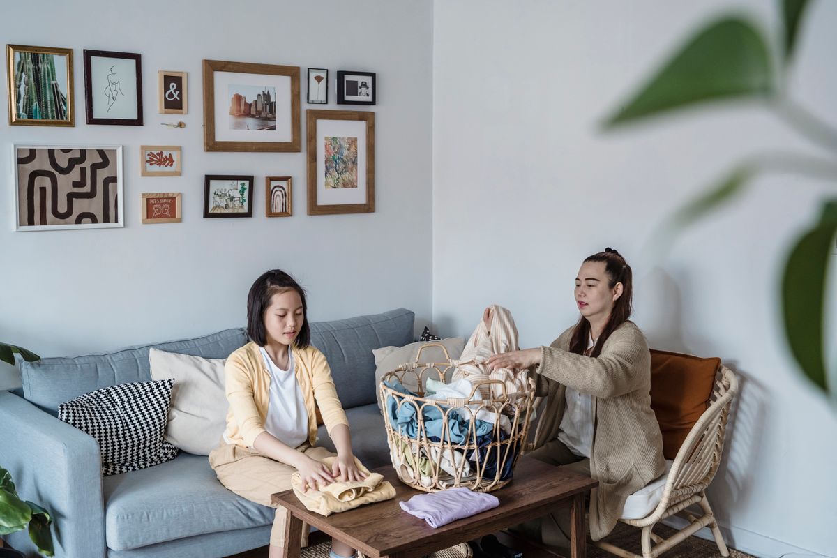 A mother and daughter engaged in folding laundry on a comfortable sofa, enhancing family bonding. - Photo by Annushka  Ahuja on Pexels