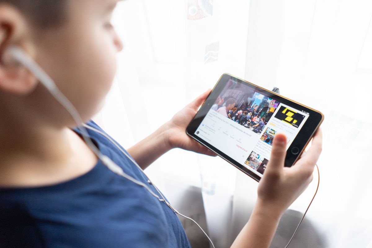 Kind hält drinnen ein Tablet, schaut sich Videos mit Kopfhörern an und zeigt, wie Kinder die Technologie nutzen. - Foto von Atlantic Ambience auf Pexels