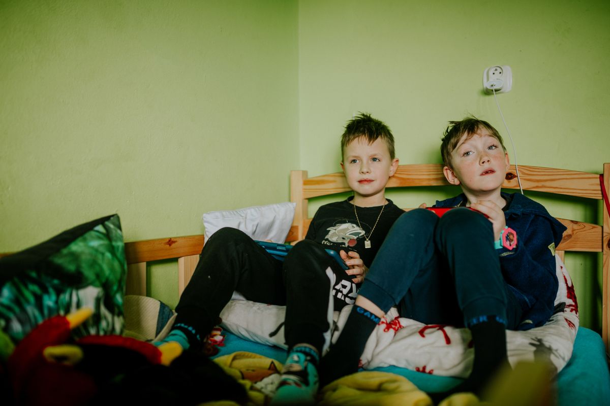 Two young boys sitting comfortably on a bed indoors, sharing a peaceful moment. - Photo by Helena Jankovičová Kováčová on Pexels