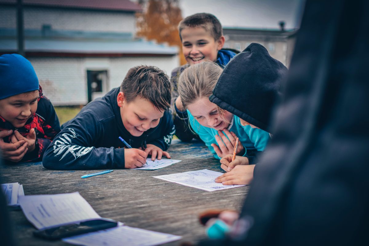 Happy children drawing together outdoors on a wooden table, fostering creativity and teamwork. - Photo by Kirill Ozerov on Pexels