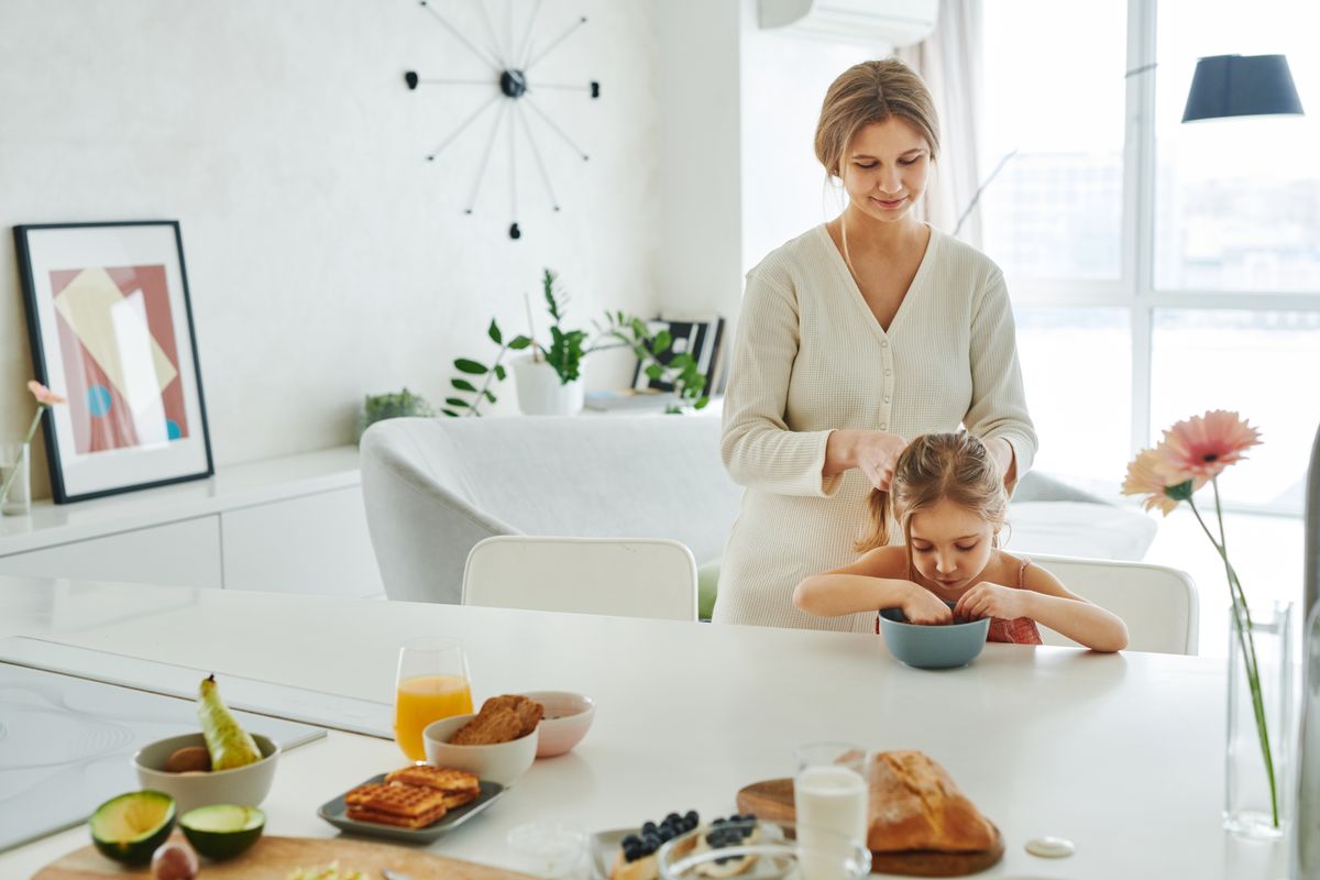 A mother braids her daughter's hair in a bright kitchen - Photo by Matilda Wormwood on Pexels