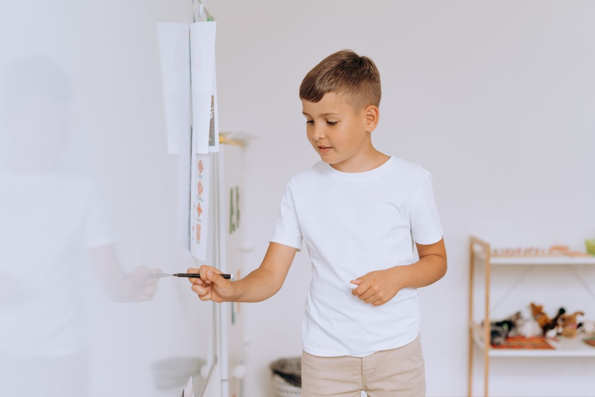 Photo by Mikhail Nilov on Pexels Kind in einem Klassenzimmer schreibt auf einem Whiteboard und konzentriert sich dabei auf Bildung und Lernen. - Foto von Mikhail Nilov auf Pexels