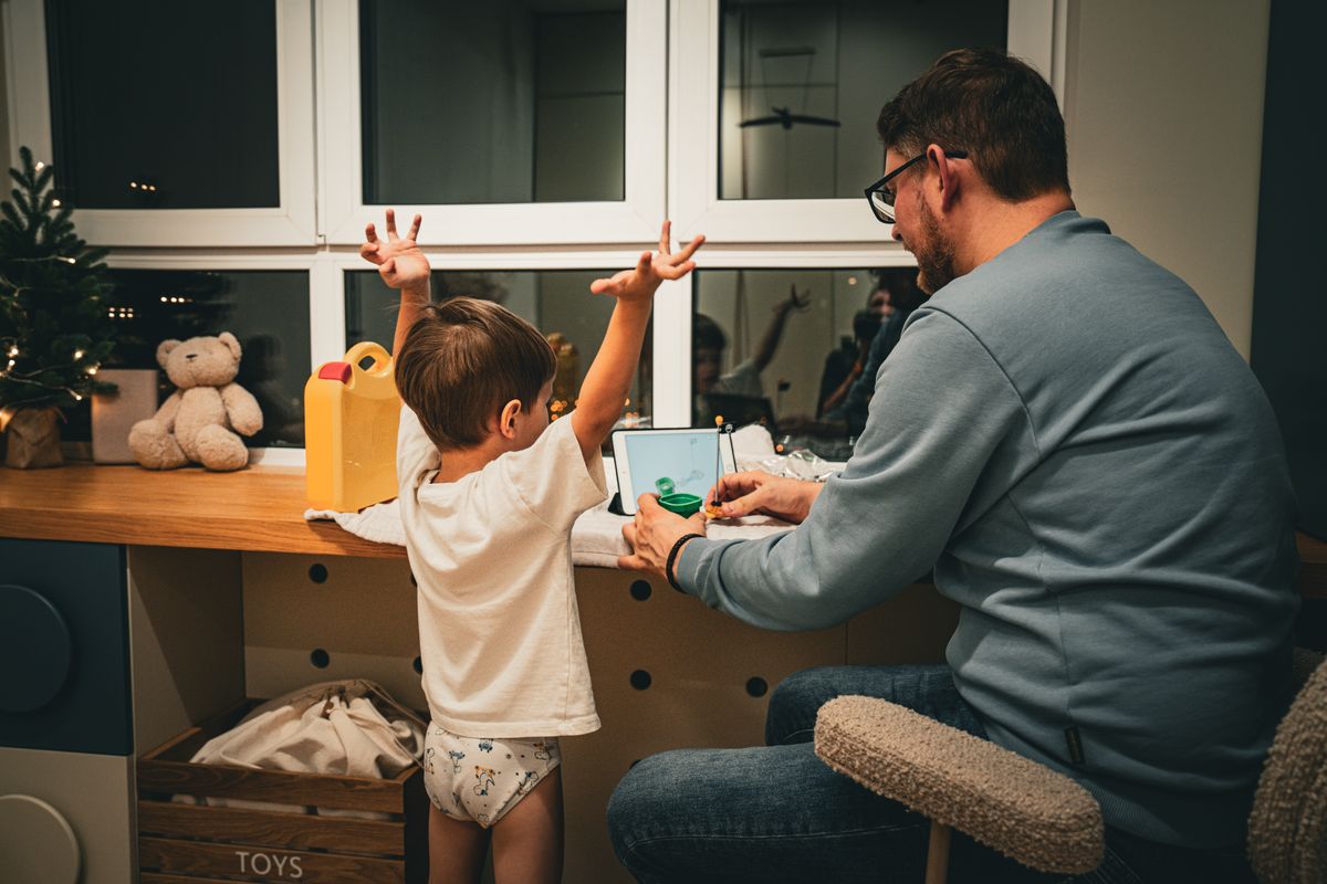 A father and child enjoy quality time together at a desk by a window in the evening. - Photo by Pexels User on Pexels