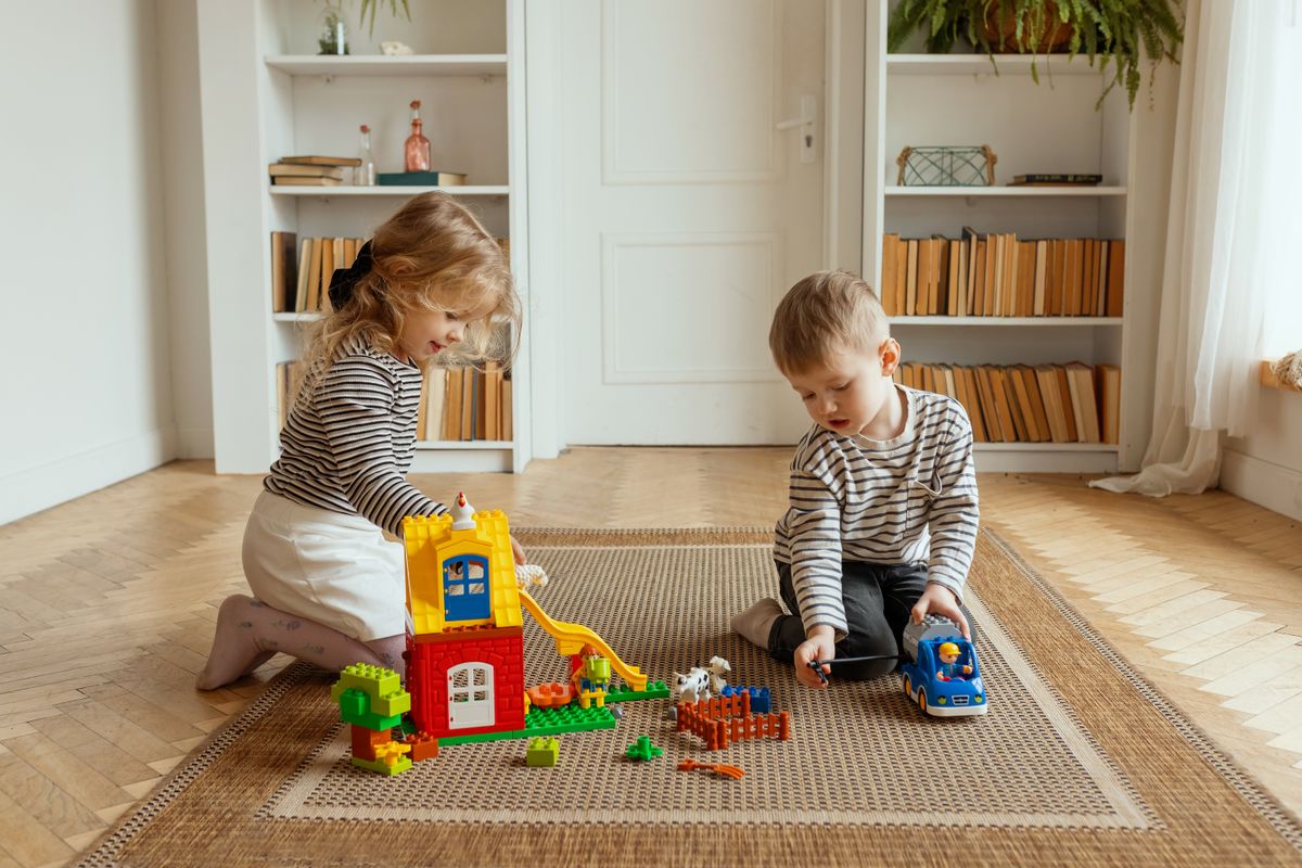 Due bambini costruiscono e giocano con blocchi colorati in casa, creando un'atmosfera giocosa e calda. - Foto di Polesie Toys su Pexels