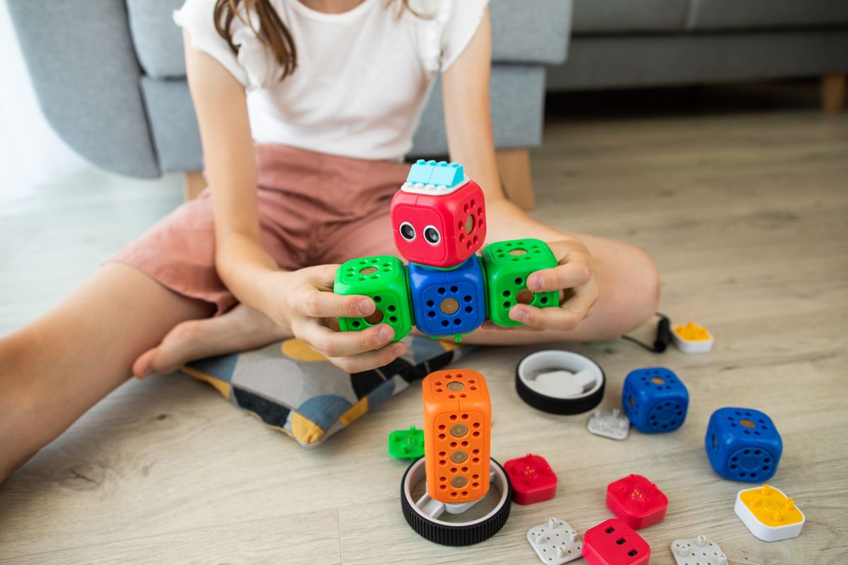 A child enjoys creativity indoors playing with a colorful robot toy, enhancing learning and fun. - Photo by Robo Wunderkind on Pexels