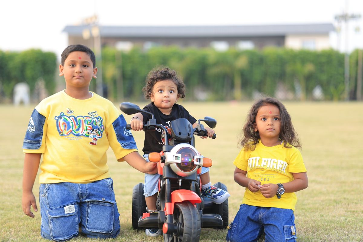 Three children enjoying outdoor play with a toy bike, capturing joyful childhood moments. - Photo by the Amritdev on Pexels