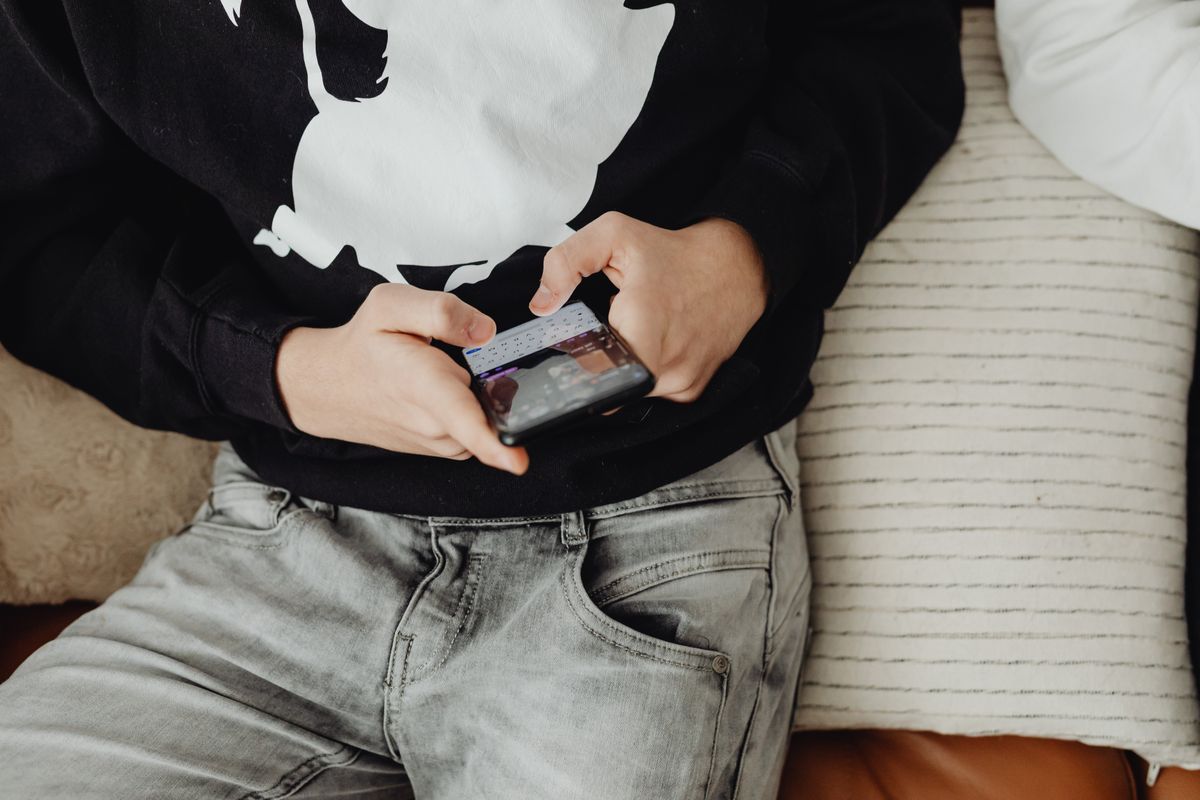Photo by www.kaboompics.com on Pexels Nahaufnahme eines Teenagers, der auf einem bequemen Sofa sitzt und ein Smartphone benutzt. - Foto von www.kaboompics.com auf Pexels