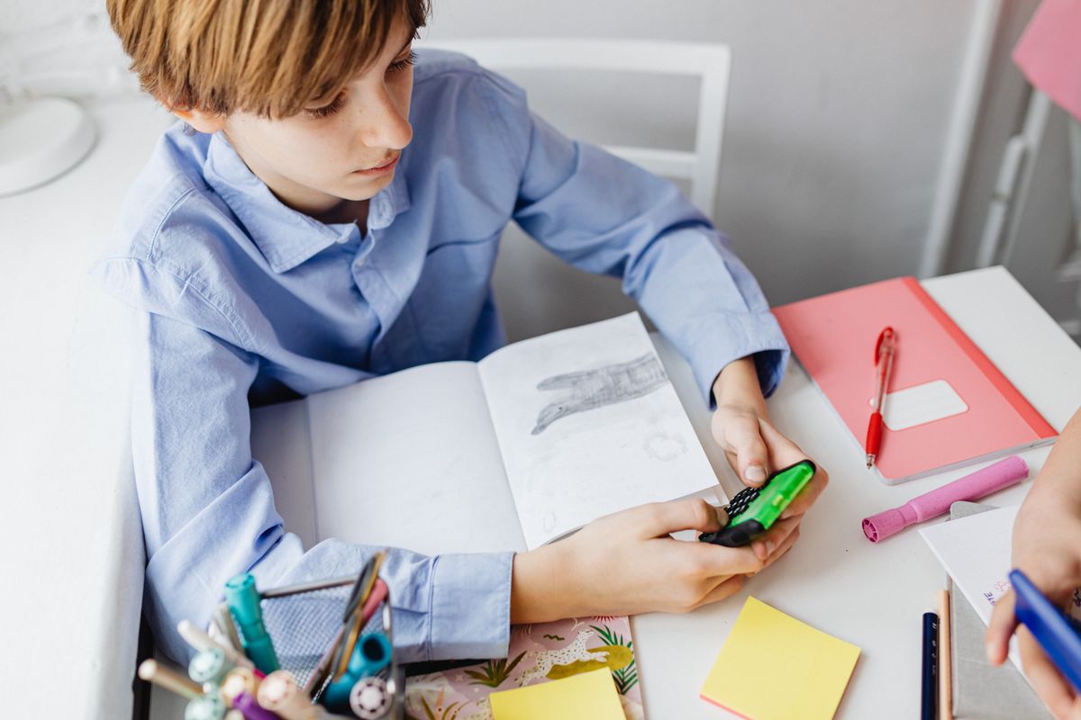 Boy using a calculator while studying at a desk with school supplies, focusing on mathematics. - Photo by www.kaboompics.com on Pexels