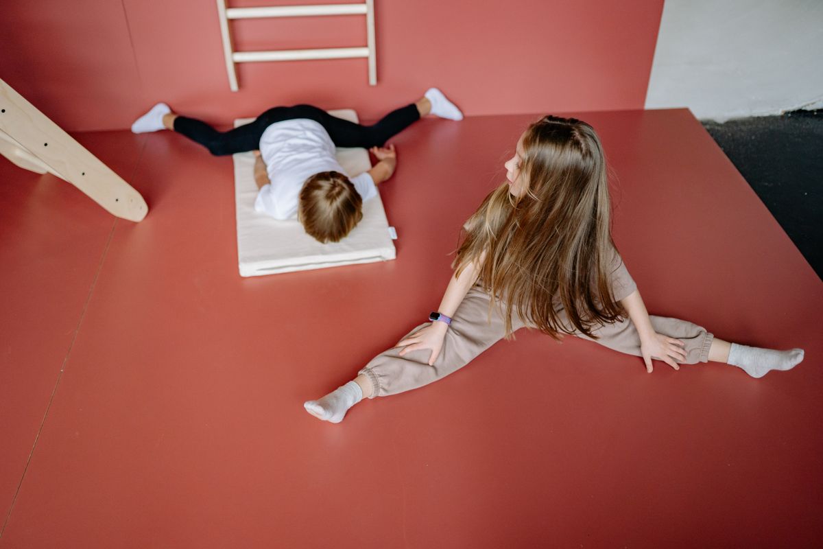 Two children engaging in gymnastics on a mat indoors, showcasing flexibility and playfulness. - Photo by Yan Krukau on Pexels