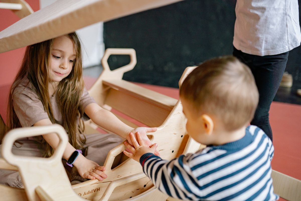 Children enjoying a playful moment with a wooden rocker indoors, emphasizing fun and interaction. - Photo by Yan Krukau on Pexels